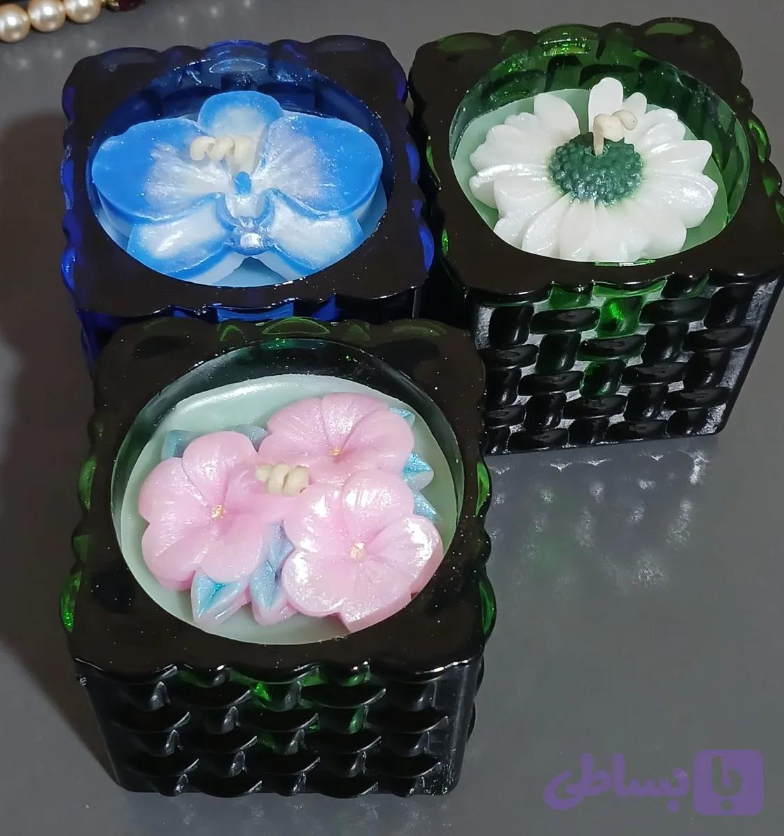 شمع شیشه‌ رنگی مربع طرح حصیری.گلهای پرطرفدار بابونه/ارکیده/سه گل بهاری. شاین‌دار ،معطر و دیرسوز.مناسب هدیه.بسته‌بندی شده