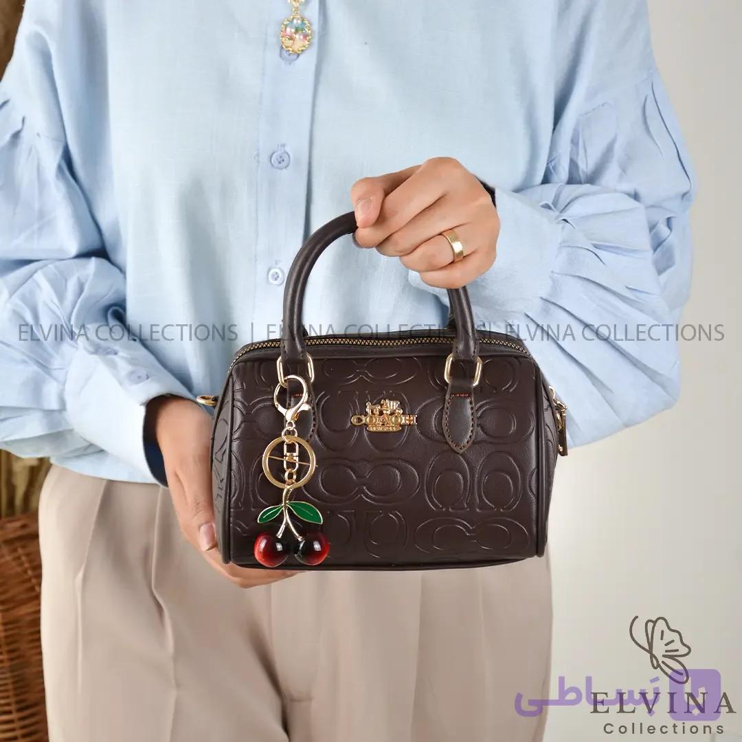 کیف دخترانه صندوقی آمیتیس طرح کوچ COACH دارای آویز گیلاس — تصویر 1